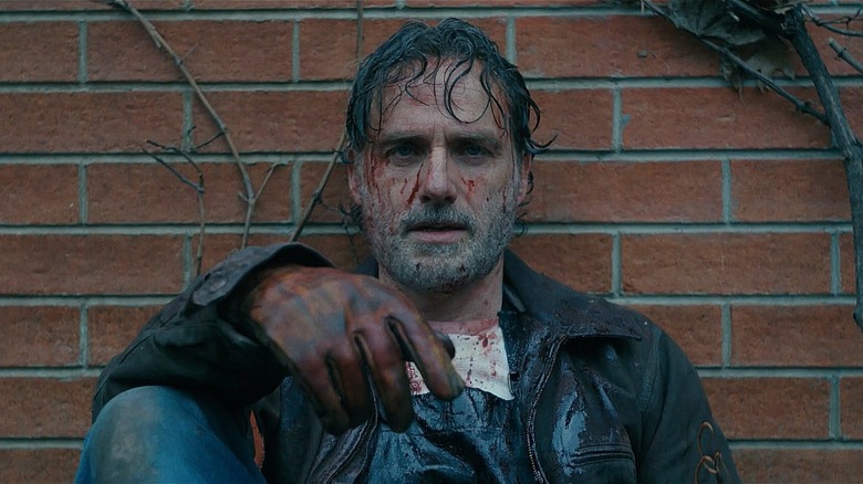 A bloodied Rick leans against a brick wall in "The Walking Dead" (2010-2022)