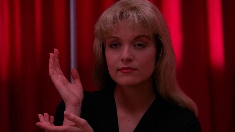Laura makes a strange hand gesture in front of a red curtain in "Twin Peaks" (1990-2017)