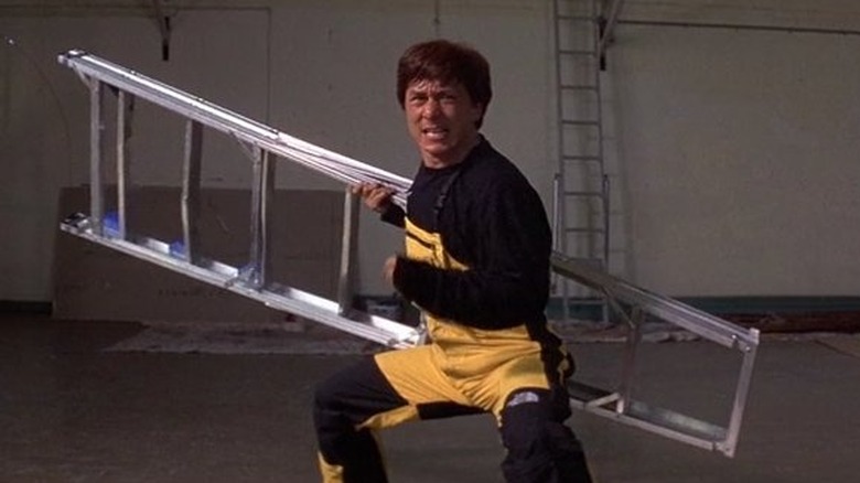 Jackie holds a ladder in a fighting pose in First Strike