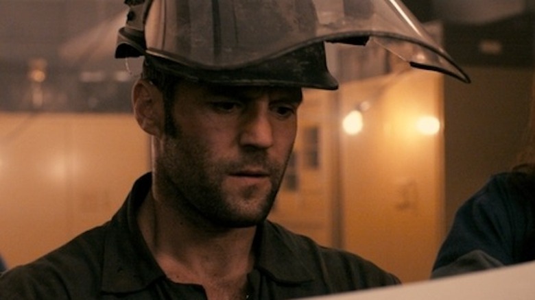 Terry, wearing a welder's mask, looks over paperwork in "The Bank Job" (2008)