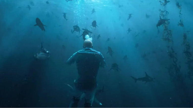 Jason Statham unerwater with multiple sharks approaching him in "The Meg"