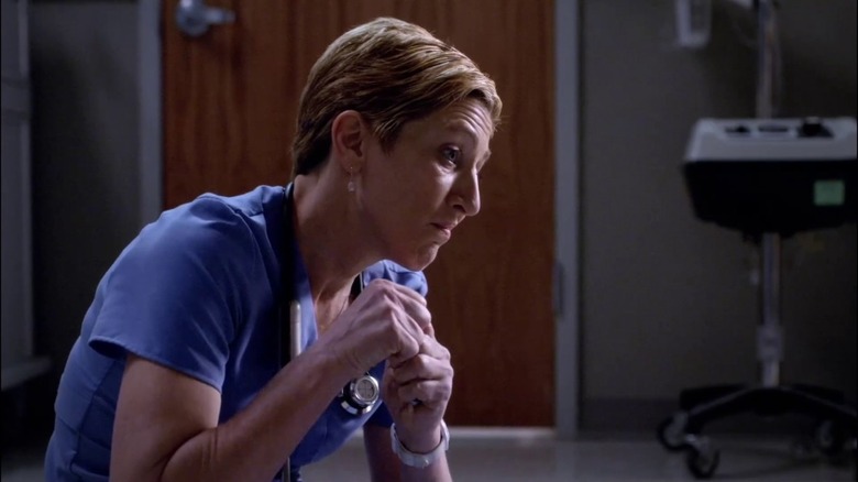 Jackie leans forward to talk to a patient in Nurse Jackie