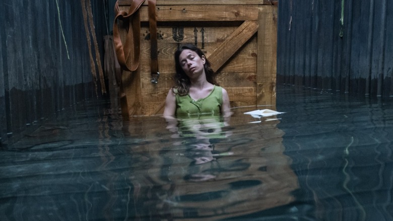 Mia sleeps in a crate full of water in "Nowhere" (2023)