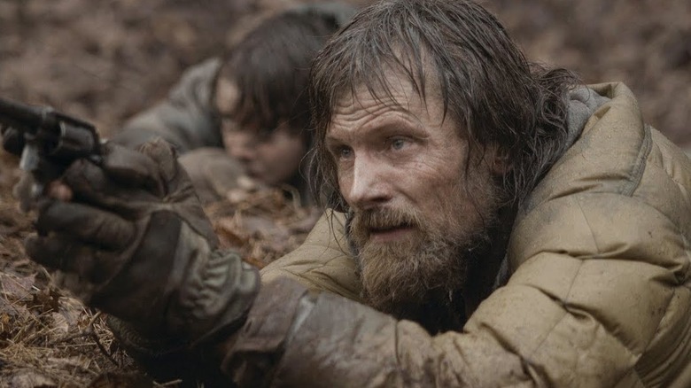 The man points a gun with the boy by his side in "The Road" (2009)