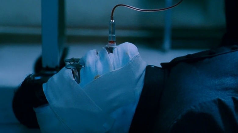 A bandaged Sang-hyun sucking blood from a comatose patient's IV in "Thirst"