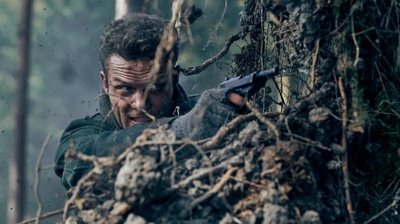 Heinrich takes aim with his pistol from behind a tree in Blood & Gold (2023)