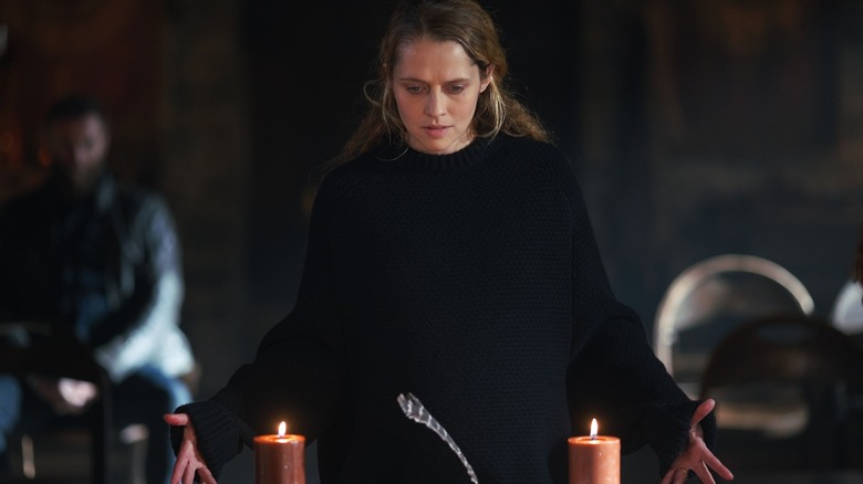 Diana doing a spell with candles and a feather