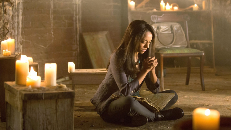 Bonnie Bennett concentrating surrounded by candles