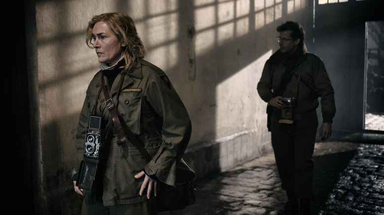 Lee Miller and David Scherman walk through a building in "Lee"