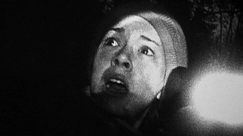 Sarah looks up while aiming a flashlight in "The Blair Witch Project" (1999)