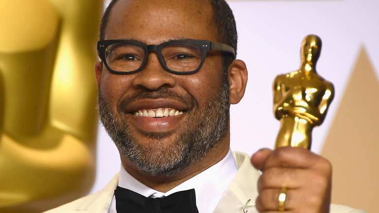 Jordan Peele holding an Oscar