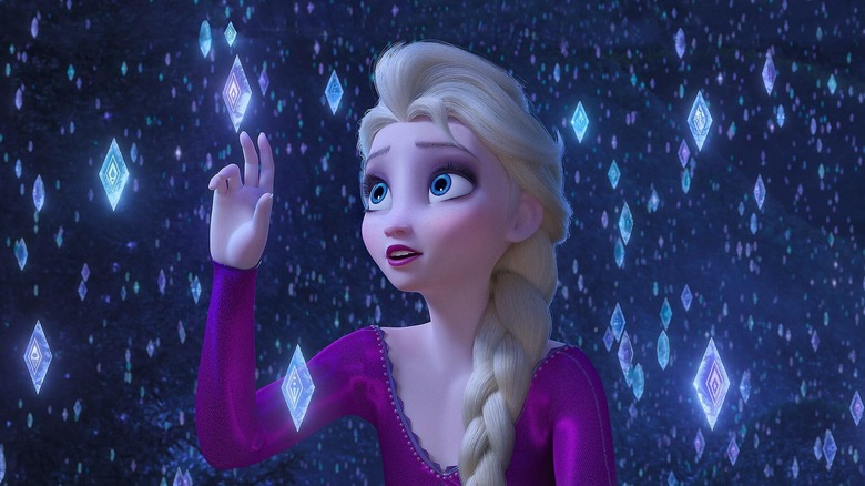 Elsa reaching up to touch ice crystals in "Frozen 2"