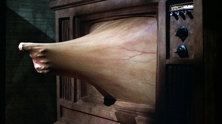 A hand reaches through the television