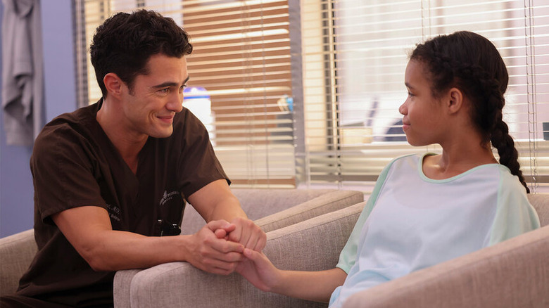 Darren Barnet as Dr. John Frost holding the hand of a young patient and smiling on Chicago Med