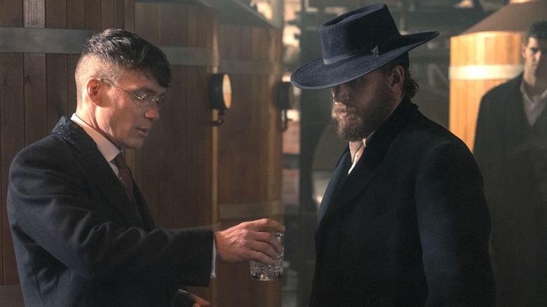 Tommy hands Alfie a drink