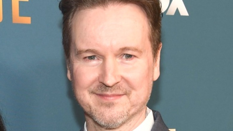 Matt Reeves smiles in front of a teal background