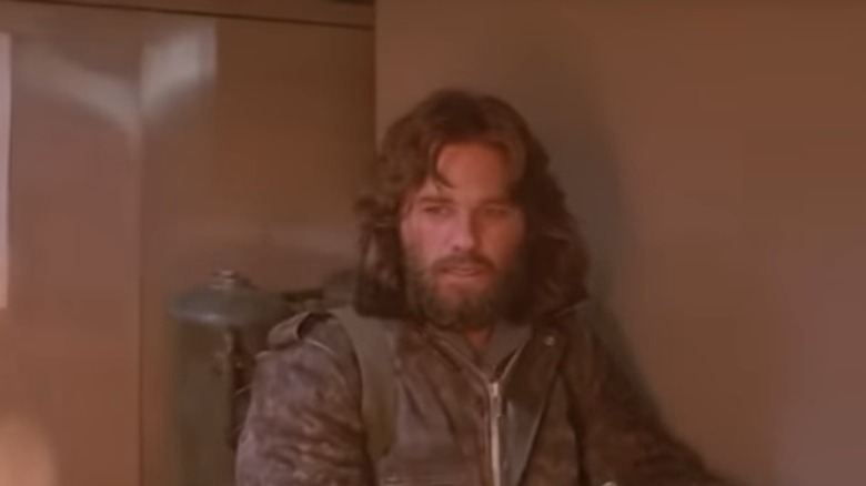 Kurt Russell standing against a wall
