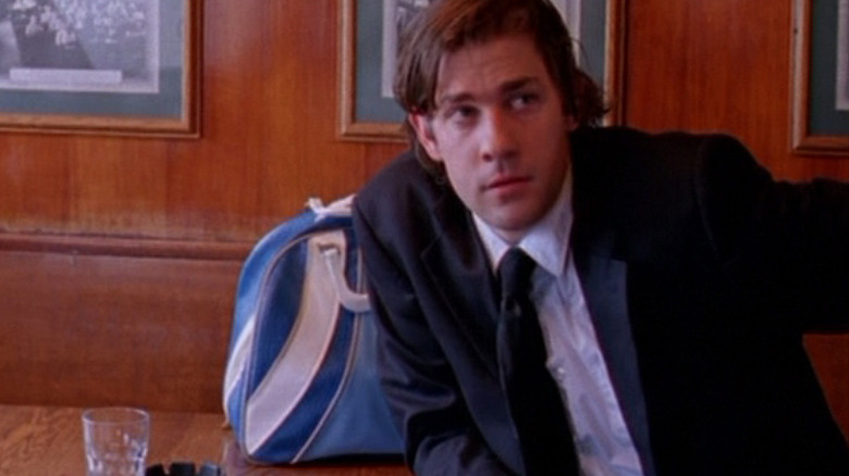 Gideon sitting in a booth with a duffel bag and a glass of water