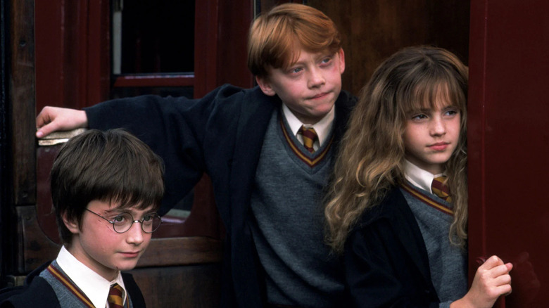 Harry, Ron, and Hermione lean on train