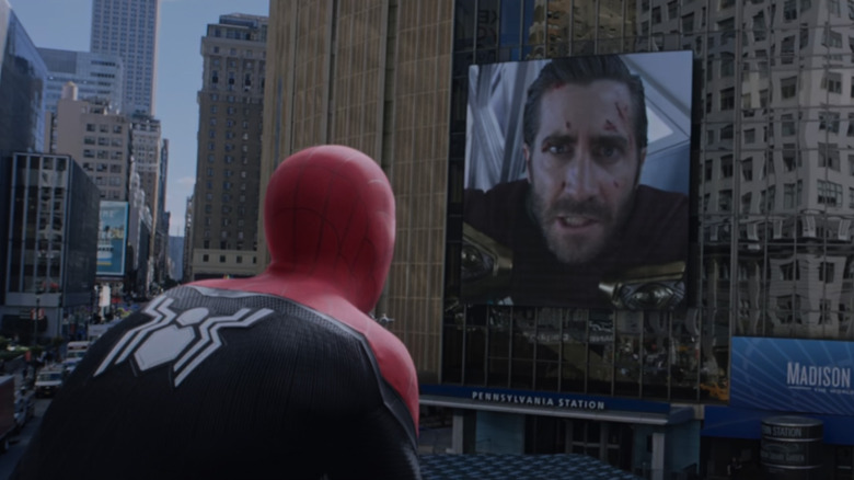 Spider-Man perched on a lamppost in Times Square and watching footage of Mysterio