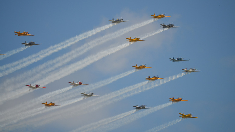 A large group of airplanes fly in formation in a blue sky