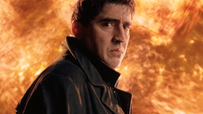 Otto Octavius looking back sadly at Peter Parker as fire looms behind him at the end of Spider-Man 2 (2004)