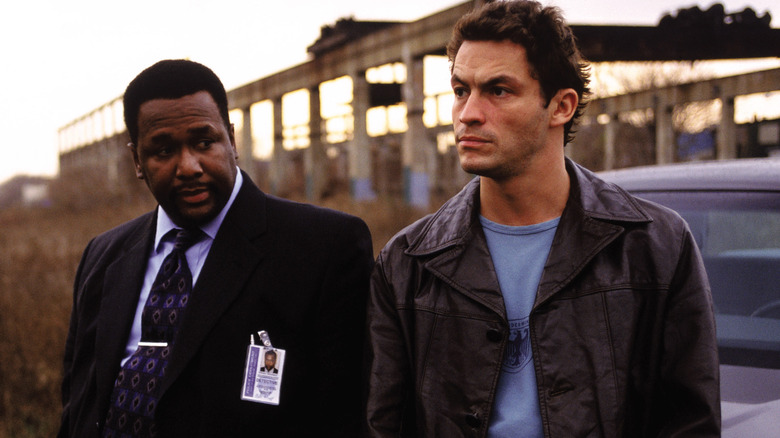 Wendell Pierce and Dominic West sitting on car