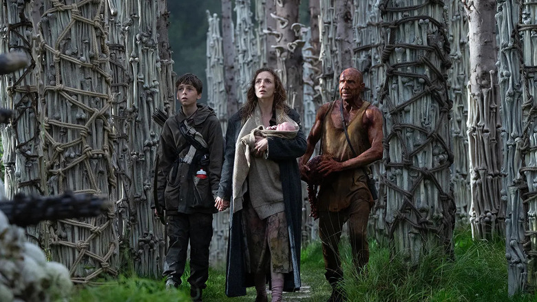 Spike Isla and Ian standing in a maze of bones and trees looking scared in 28 Years Later