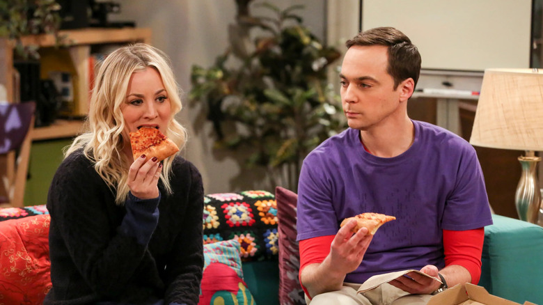 Penny eating pizza while Sheldon watches on The Big Bang Theory