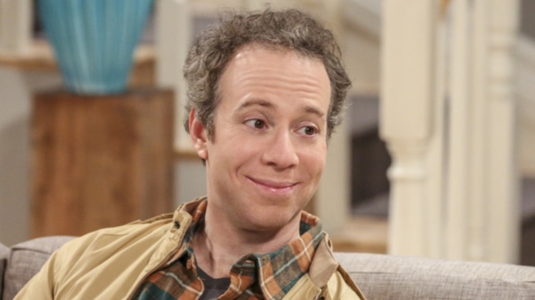 Stuart Bloom leans over and talks on The Big Bang Theory