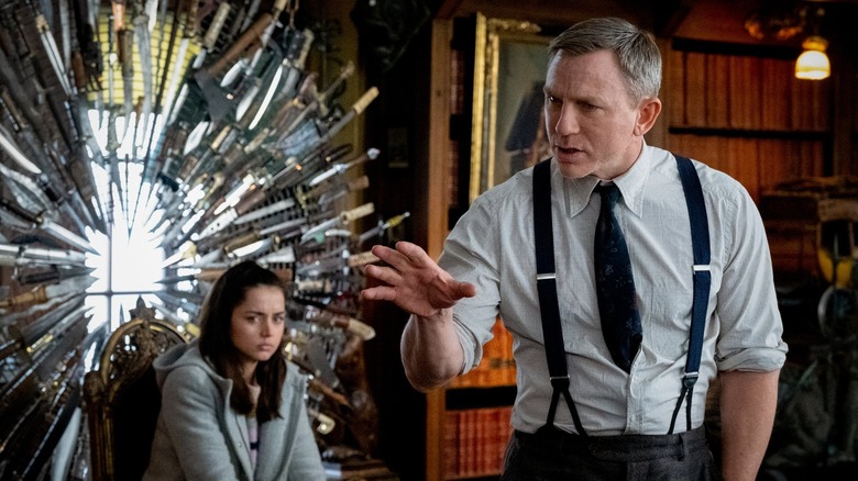 Benoit Blanc explains the case with Marta behind him in 