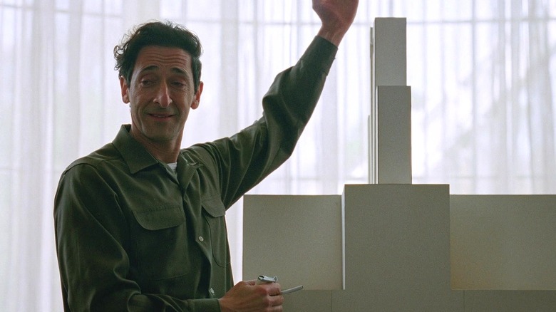 László Tóth presents a model of the community center in "The Brutalist" (2024)