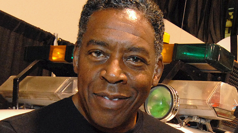 Ernie Hudson smiling in front of Ghostbusters car