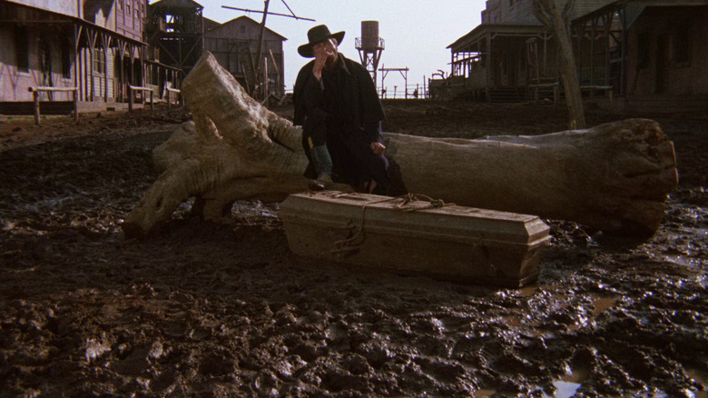 Franco Nero as Django sitting outside on fallen tree trunk