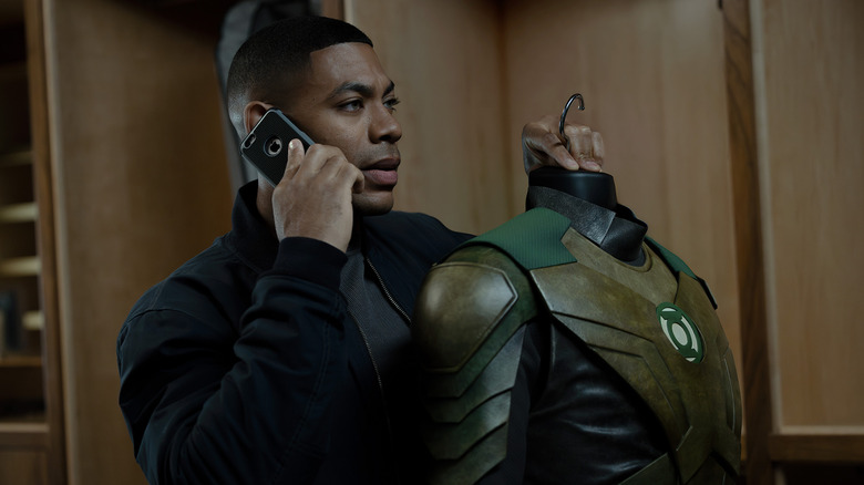 John Stewart holding a Green Lantern uniform and speaking on the phone on Lanterns