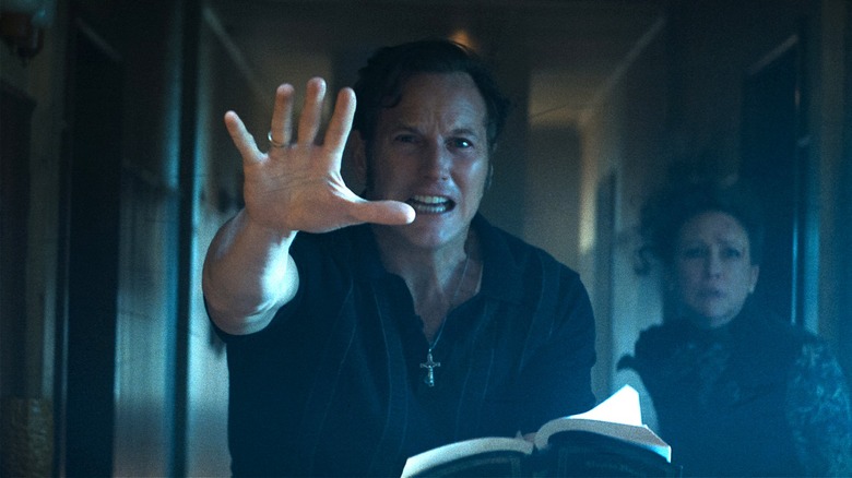 Ed Warren doing an exorcism while Lorraine stands behind him in The Conjuring: Last Rites