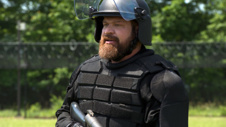 Brad William Henke as Desi in riot gear