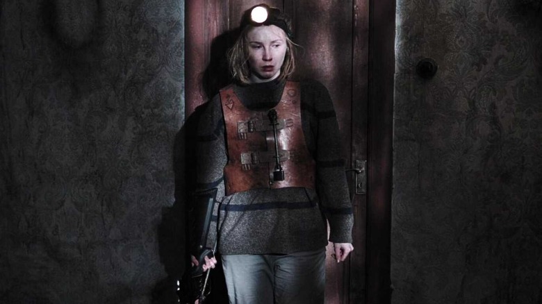 Olga wearing Isaac's restraint and carrying a crossbow in "Caveat" (2021)