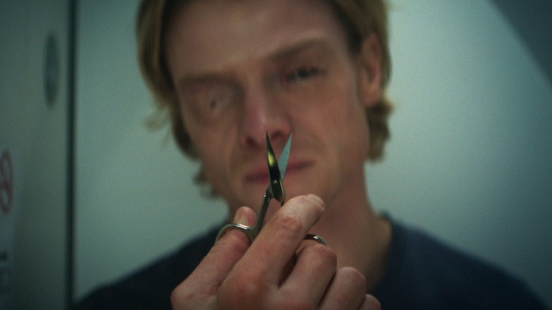 Matt Hagen staring at tiny scissors to help with his skin problems in "Clayface" (2026)