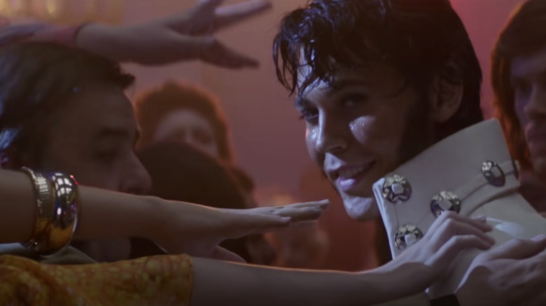 Elvis smiles as the hands of fans reach out to him