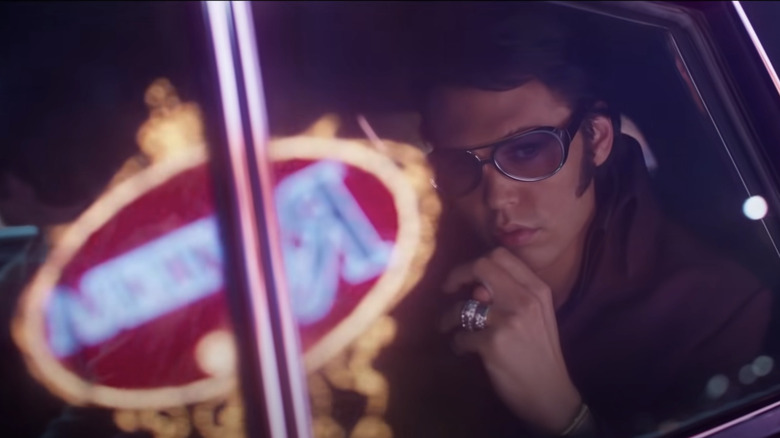 Elvis looks out through a car window with the reflections of Vegas lights