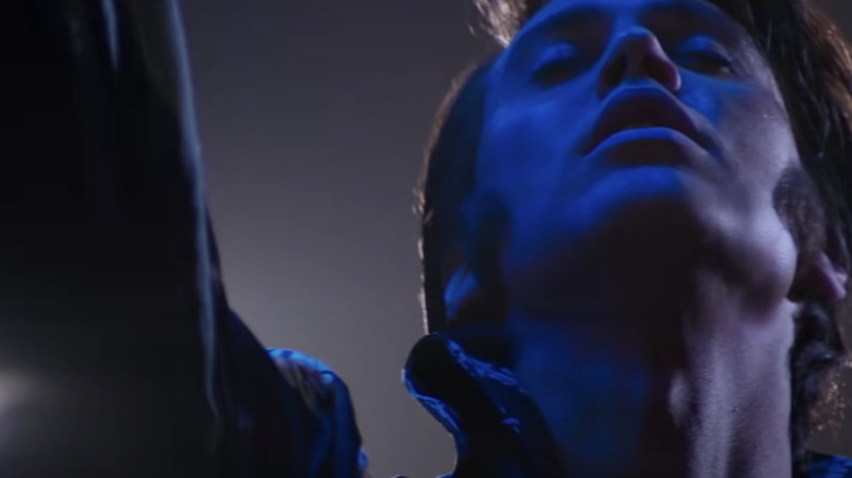 Elvis points up, bathed in blue light