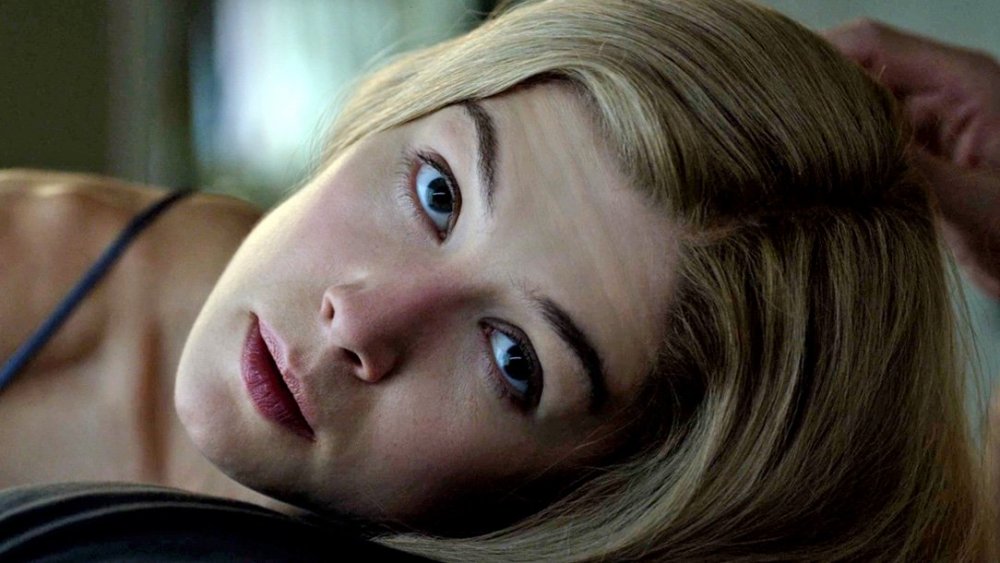 Immagine tratta dal film L'amore bugiardo, con l'attrice Rosamund Pike che, sdraiata, solleva la testa e guarda verso l'obiettivo.