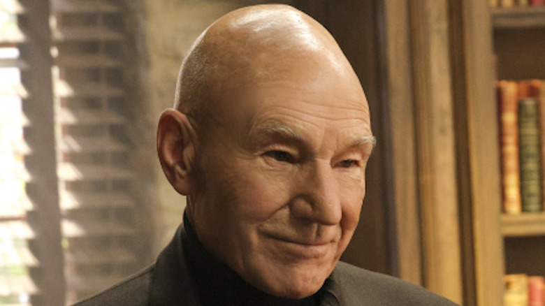 Picard smiling and standing in front of bookshelf