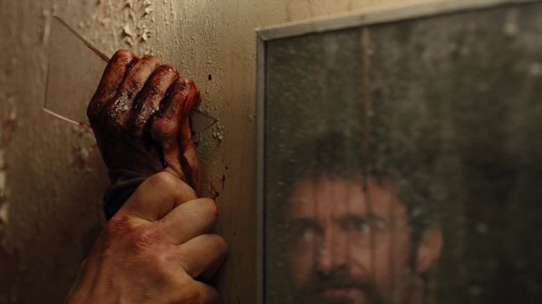 Αιματηρό χέρι που κρατάει το γυαλί με Hugh Jackman στον καθρέφτη