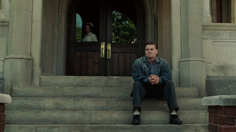 Teddy sitting alone on the stairs while a nurse looks at him from inside