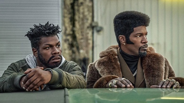 Tyrone and Slick Charles stand by a car, looking off camera