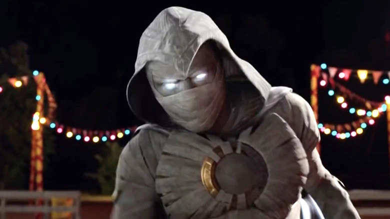 Moon Knight in costume at night with lights behind him in "Moon Knight" (2022)