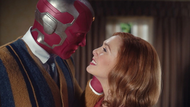 Wanda and cardigan-wearing Vision embracing in their idyllic home in "WandaVision" (2021)