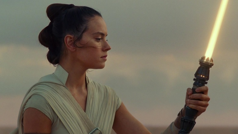 Rey holding yellow lightsaber